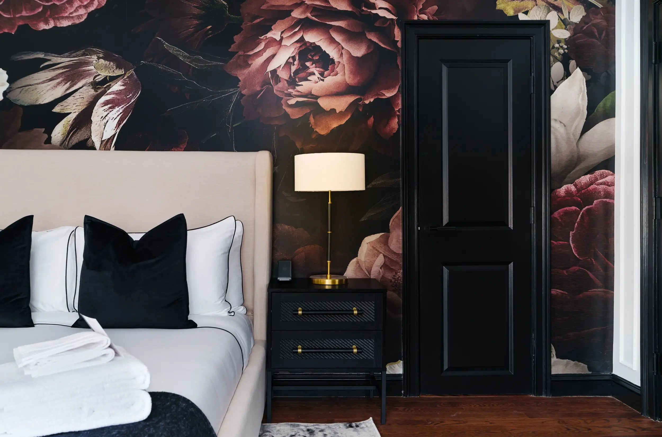 Guest suite at Garden Gables Inn in Lenox with dark floral wallpaper and a brass bedside lamp